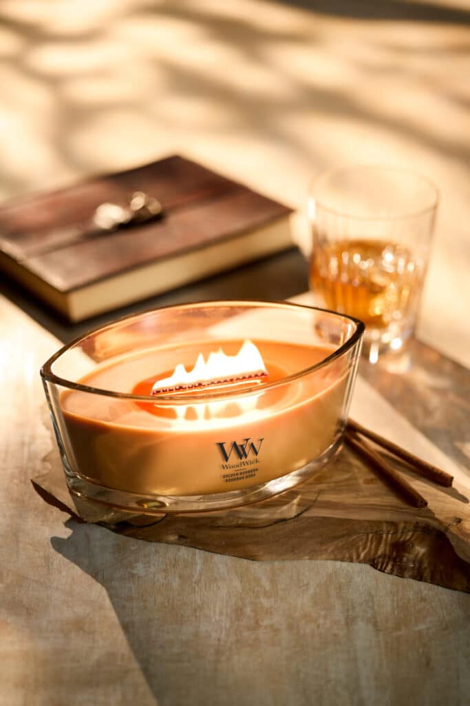 Ljuslykta med varm låga, bok och glas, skapar en mysig atmosfär.