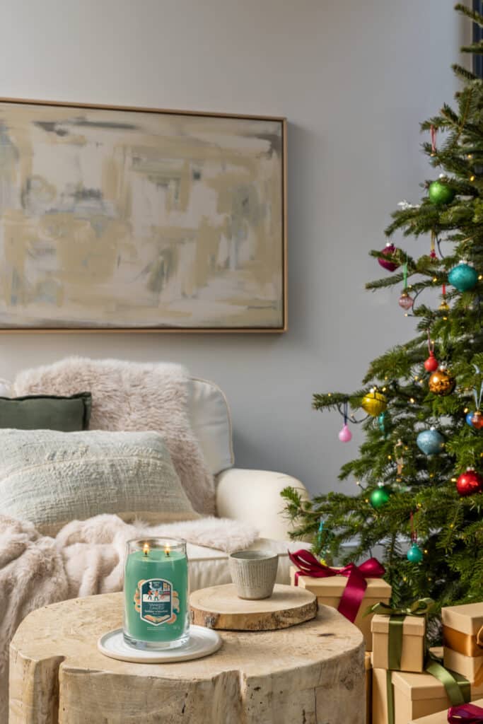 Mysig julscen med tändt ljus, gran och presenter i modernt vardagsrum.