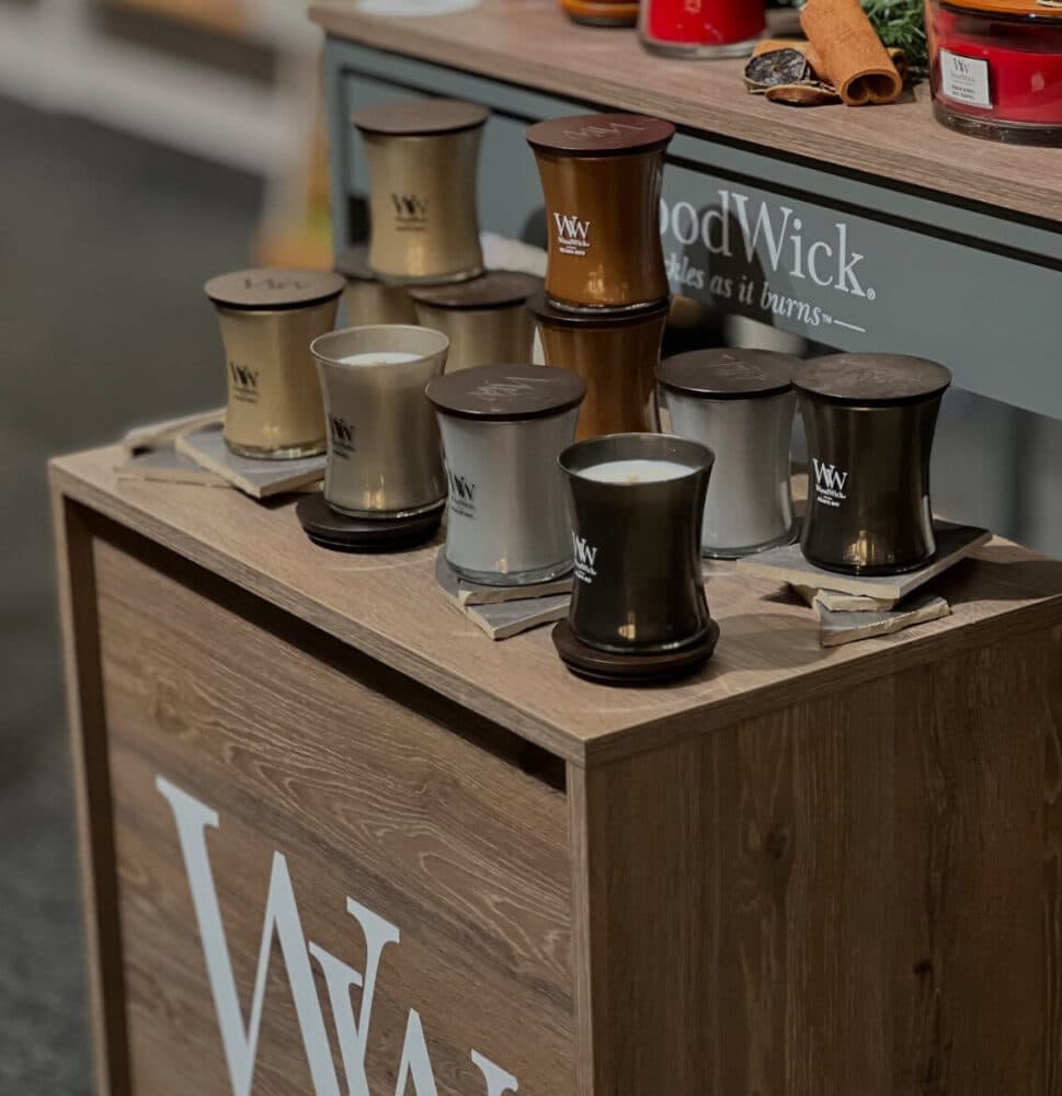 Trädoftande WoodWick-ljus i olika färger på trädisplay.