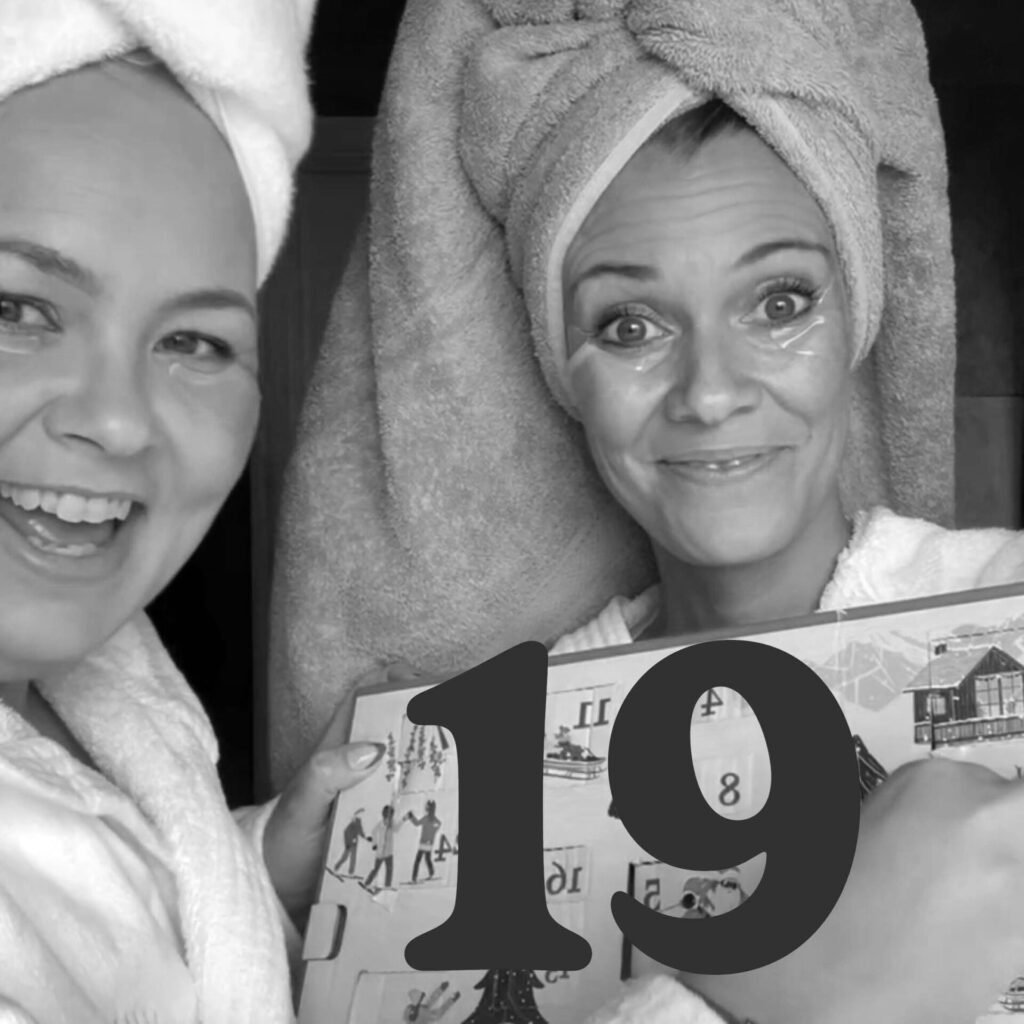 Två personer med handdukar och ögonmasker visar en adventskalender, siffran 19.