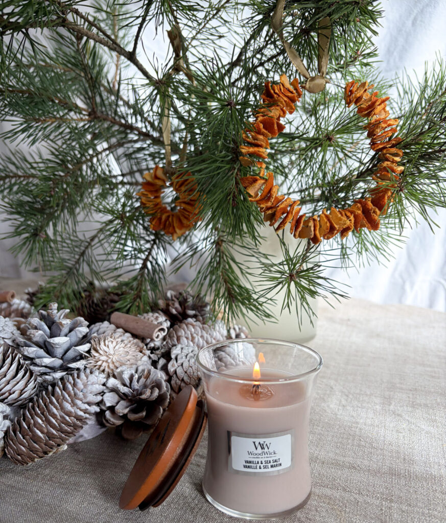 Doftljus med granris och torkade apelsinskivor för en mysig vintrig dekoration.