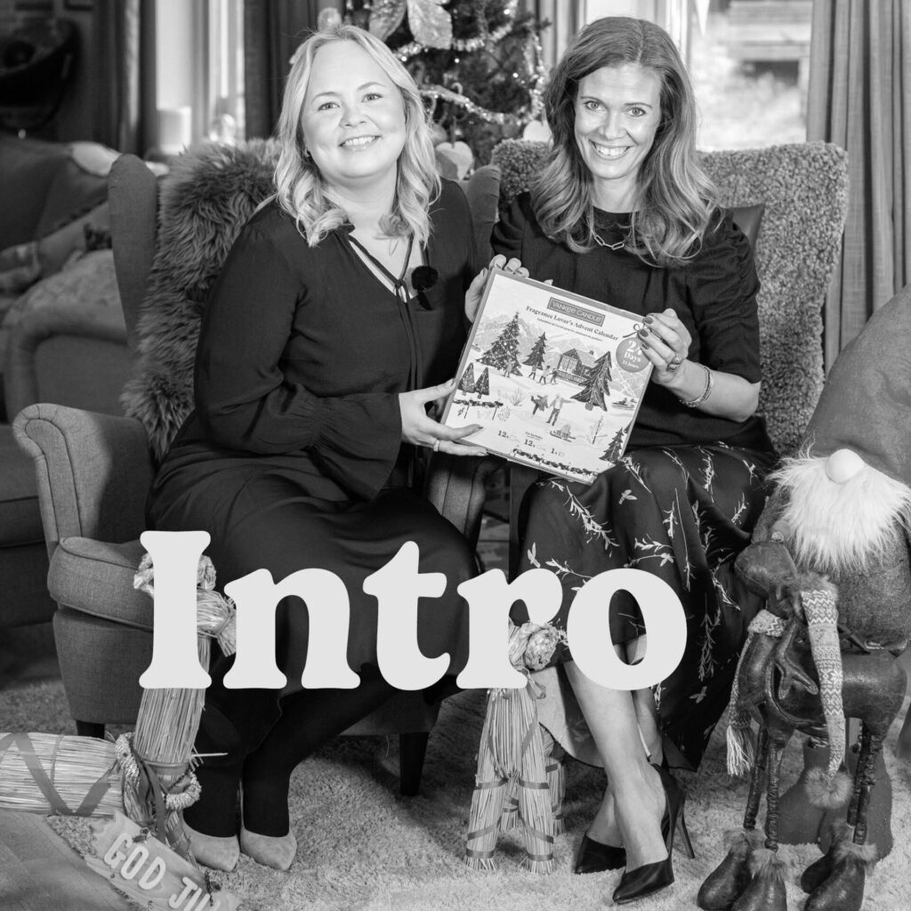 Två personer sitter med en julkalender, juldekorationer i bakgrunden.