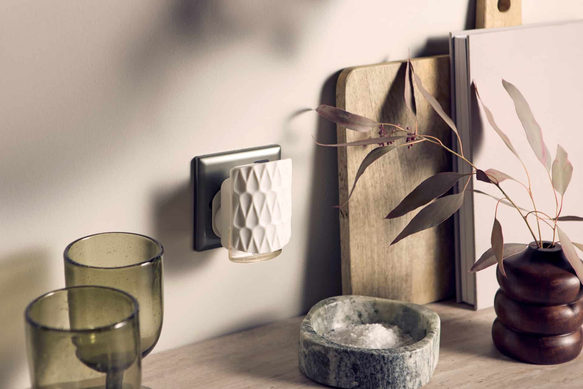 Stilren rumsdoft i eluttag vid modern köksbänk med växt och keramiska detaljer.